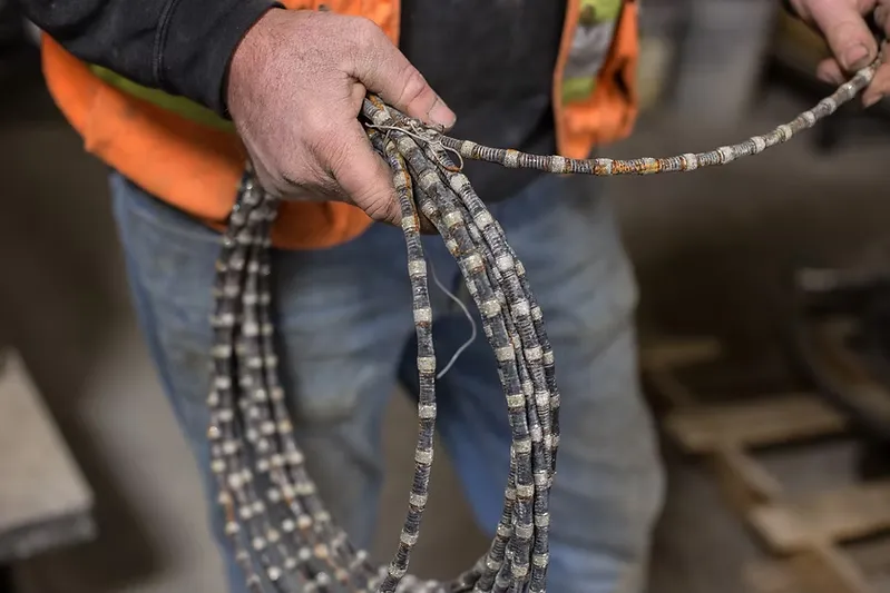 A person wearing a safety vest holds a coiled diamond wire used for cutting stone or concrete, perfect for illustrating techniques in a construction blog.